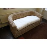 A contemporary wicker three-seater patio or conservatory sofa with fitted cushion, 180cm wide