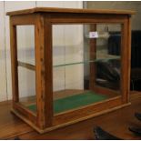 An early 20th century shop counter display cabinet with slide-up door and glass shelf,