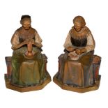 A pair of black forest wood figurines of two ladies, one knitting and the second peeling potatoes on