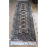 A Pakistani hand knotted woollen rug, beige ground with multicoloured isometric designs, 59cmx 180cm