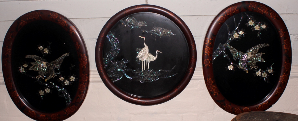 Two oval and one circular Japanese mid-20th century lacquered wall panels with mother of pearl avian