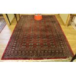 A multicoloured burgundy-ground floor rug with isometric designs and double border with long fringe,