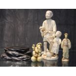 An early 20th century Japanese ivory sectional okimono depicting a man and boy on a stylized base,