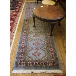 A Middle Eastern-style hand knotted blue ground multicoloured floral runner, 295 cm x 80 cm