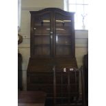 An Art Nouveau oak bureau bookcase with dome shaped cornice, twin astragal doors with stained glass,