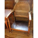 A early 20th century hardwood conservatory chair with rattan support, carved arm rests, raised on