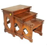 An early 20th century oblong nest of three oak tables with fret work to the side panels on trestle