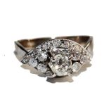 An 18 carat white gold dress ring, claw set with one central brilliant cut diamond and flanked at