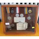 A selection of Festival of Britain Crown coins 1951, with old war medals in an oblong display case