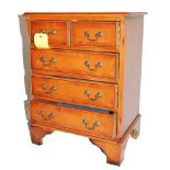 A Georgian-style yew wood and cross banded miniature chest or bedside locker with shaped top, two