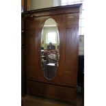 An Edwardian mahogany and cross banded wardrobe with shaped cornice, oval mirror on central