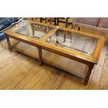 A mid 20th century French-style walnut coffee table of oblong form with glass top, shelf under