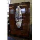 An Art Deco mahogany and cross banded wardrobe with shaped cornice, oval bevelled mirror to