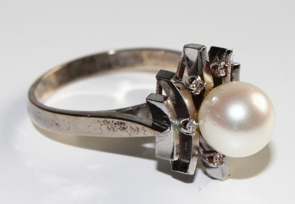 An 18 carat white gold cluster dress ring, set with one central 8mm cultured pearl, surrounded by