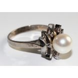 An 18 carat white gold cluster dress ring, set with one central 8mm cultured pearl, surrounded by