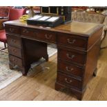 A Georgian-style twin pedestal desk with tooled leather inset, shaped top, eight small and one