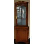 A Georgian-style yew wood corner cabinet with shaped cornice, single glazed door, shelved interior