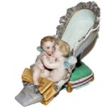 A late 19th century Dresden figurine of a lady's shoe with two embracing cherubs to the front on a