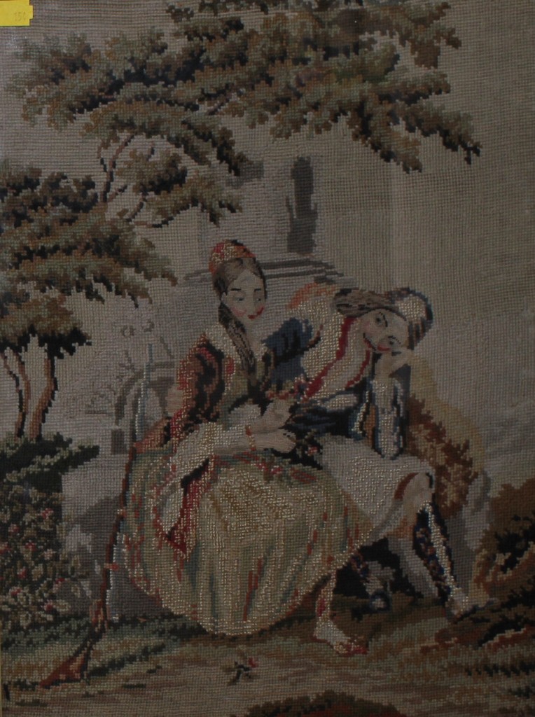 A Victorian wool embroidery of a woman and gent seated, framed, 40cm x 30cm