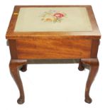 An early 20th century mahogany music stool of oblong form with embroidered lift-up seat, raised on