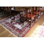 An Aztec-style red-ground drawing room rug with treble border, isometric multicoloured designs