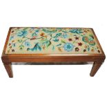 An Edwardian mahogany framed footstool of oblong form with multicoloured stitched embroidered top,