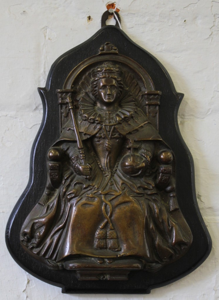 A Victorian bronze plaque mounted on a wooden base of a seated queen holding a sceptre and globe,