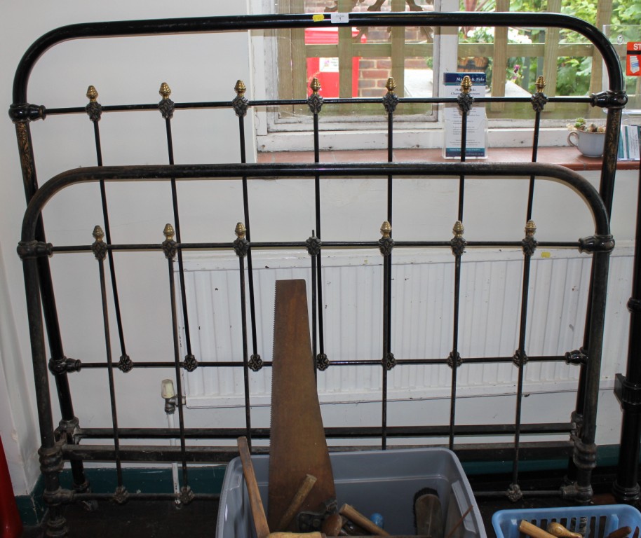 A late 19th century black painted metal bed frame with spindle supports and brass finials, 140cm