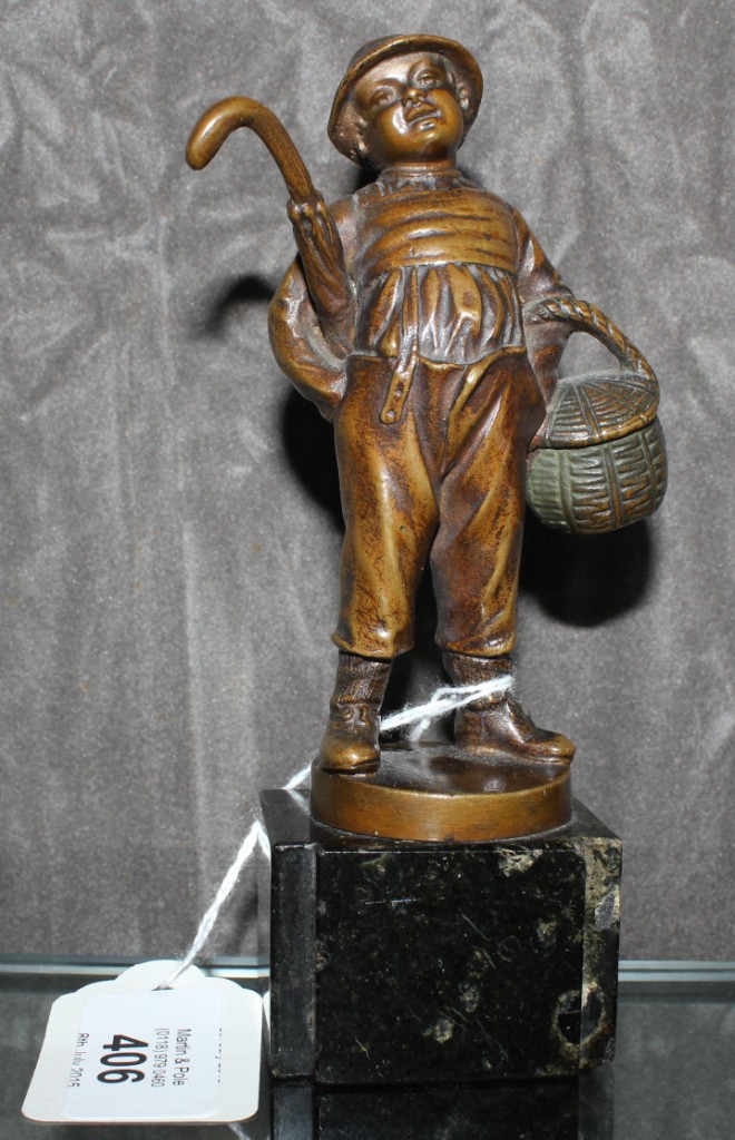 A small bronze of a boy with umbrella and basket signed R.W. Lang