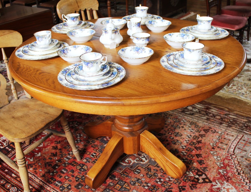 A Victorian-style light oak circular dining table, moulded top with fold away extra leaf, raised