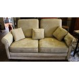 A contemporary fabric upholstered three seat sofa in cream suedette, with removable cushions, shaped