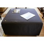 A square fabric upholstered Ottoman on wooden block feet, 47H x 93W x 93cmD