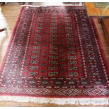 A Middle Eastern-style red-ground hand knotted wool rug with multicoloured isometric designs with