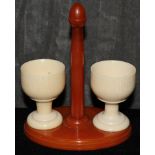 A pair of ivory egg cups on a catalin stand, 14cm  The Art Deco Carvings of W. G. Collins (1872-