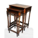 An early 20th century oak stained nest of three oblong tables with bobbin shaped legs and