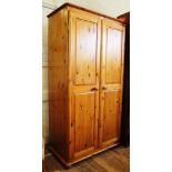 A contemporary pine wardrobe with shaped cornice, two panelled doors, fitted for hanging with a