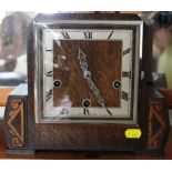 An Art Deco oak-stained mantle clock with square dial, Roman numerals on a stylized base