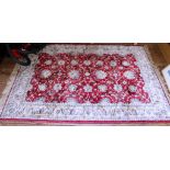 An Oriental red-ground rug of oblong form with ivory border with floral and foliate designs with