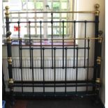 A Victorian metal black painted bed end with spindle supports and brass fittings and castors,