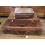 Three vintage suitcases with metal mounts and leather handles