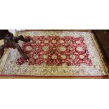 An Oriental red-ground rug of oblong form with ivory border with floral and foliate designs with