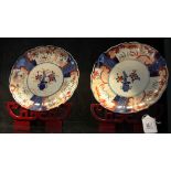 A pair of early 20th century Japanese Imari circular plaques on stands with blue and ochre foliate