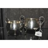 A silver sugar bowl on three lion paw feet and matching cream jug, both with hammered finish,