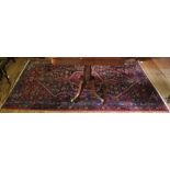 A Middle Eastern-style red-ground hand knotted wool rug with multicoloured isometric designs with