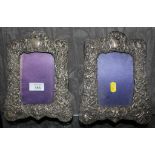 A pair of silver photo frames, highly decorated in relief, 9.5" x 7", Birmingham 1903, one stand