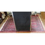 A Middle Eastern-style red-ground hand knotted wool rug with multicoloured isometric designs with