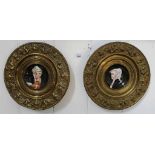 A pair of circular enamel portraits of 19th century ladies on porcelain saucers with highly ornate