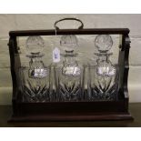 A quality three-decanter mahogany and brass Tantalus with pull-out brass knob release, including