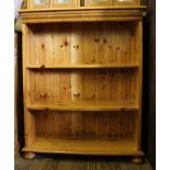 A pine free standing bookcase with shaped top, three shelves under, raised on bun feet, 102H x 80W x