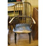 An early 19th century Windsor-style elm seated kitchen chair with spindle supports, carved arm